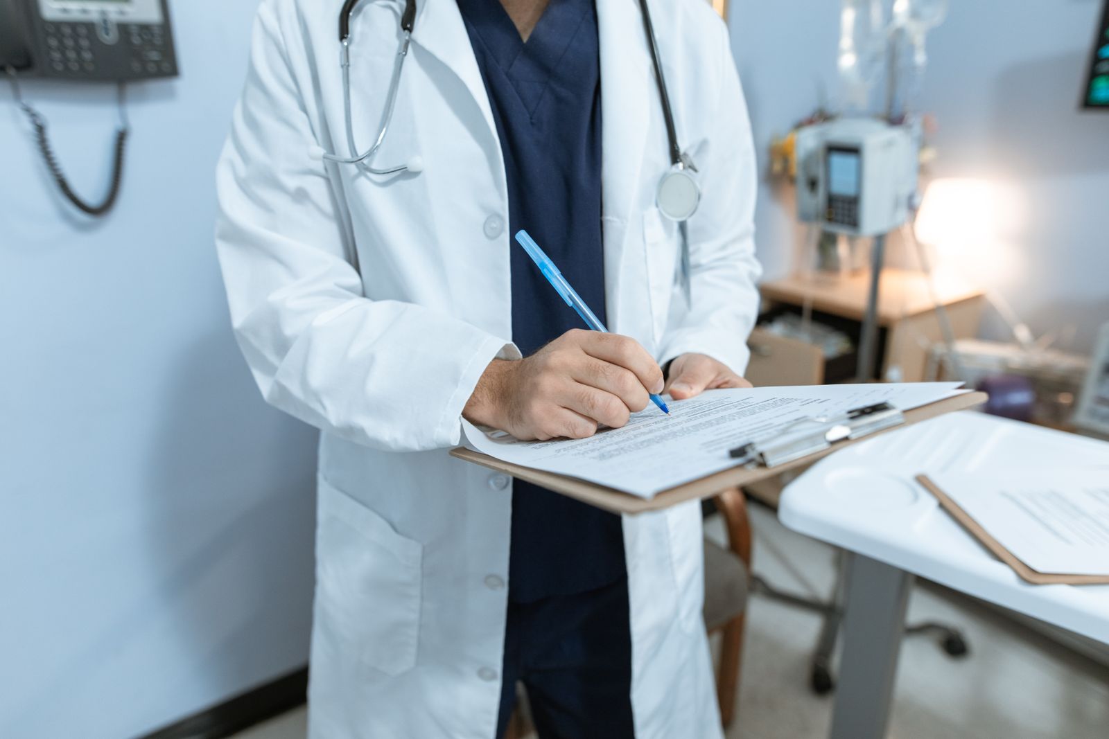 Doctor reviewing and writing on a medical chart in a hospital